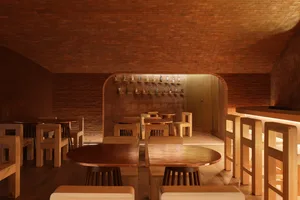 A restaurant interior with wooden tables and chairs arranged throughout the space, creating a comfortable and inviting atmosphere