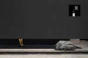 A gold statue stands in front of a black wall, creating a sense of mystery and intrigue