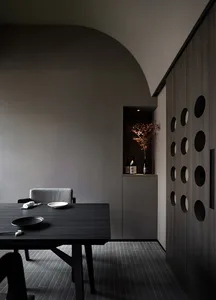 A dining area with a wooden table surrounded by chairs, featuring three bowls and two bottles, creating a cozy and functional setup
