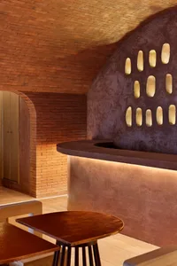 Warm and inviting restaurant interior with a brick wall, wooden tables, and a bench, creating a cozy atmosphere
