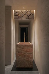 Bathroom with a stone-walled alcove featuring a marble sink and large rocks on the walls, creating a calm and serene atmosphere
