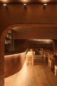 Cozy restaurant interior with wooden floors, brick walls, and dim lighting, featuring tables and chairs in a rustic setting