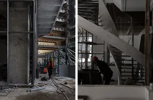 Construction workers on the ground level of an underground building, with a staircase leading down to multiple levels