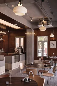 Inviting coffee shop interior with wooden accents, tables, chairs, and a bar counter, featuring multiple cups and a comfortable atmosphere