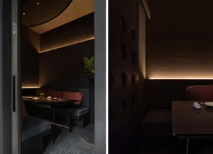 Dimly lit restaurant interior with wooden elements, dining tables, and chairs, creating a cozy atmosphere