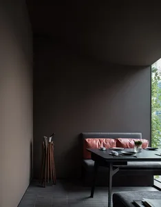 A darkly colored dining room with a table and chairs, two couches, and a vase adding to the cozy ambiance