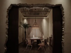 Modern open concept dining space with a white tablecloth, a dining table, and a kitchenette with a sink and refrigerator