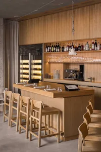 A warm and inviting bar area with a wooden countertop, wine bottles, and comfortable seating for patrons