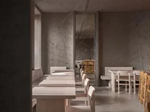 A calm and inviting restaurant interior with multiple tables and chairs, varying in size and shape, set up for guests to enjoy their meals