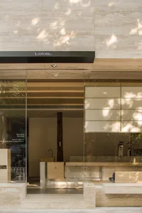 A well-lit showroom with glass doors, a sink, a chair, and various items on display, surrounded by natural light from a large window