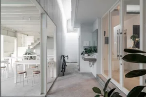 A casual living space with a dining table, two chairs, and a bicycle, set against a neutral background
