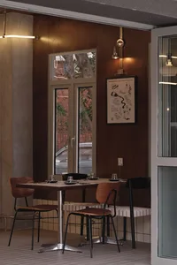 Warm and inviting restaurant interior with wooden tables, chairs, and wine glasses, conveying a comfortable atmosphere for diners