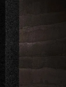 A dark stone wall with a black door, giving an old and mysterious atmosphere