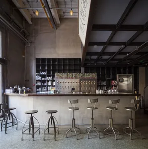Industrial bar area with a long concrete countertop and several stools, giving off a calm atmosphere