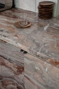 A modern kitchen with a marble countertop, sink, and cup, featuring a luxurious and sophisticated design