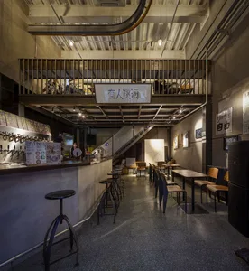 A casual restaurant with multiple dining tables and chairs, bottles on surfaces, and a warm atmosphere
