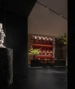 Dark room with a black marble countertop, vases, and multiple chairs, creating a luxurious and stylish atmosphere