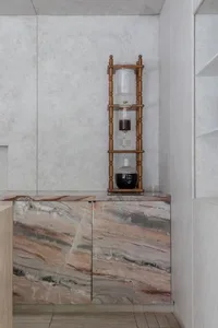 Elegant kitchen with a marble countertop, wooden cabinetry, and decorative vases, set for dining or entertaining