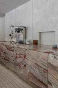 A clean and organized kitchen with a marble countertop featuring cups, bowls, and a blender, adding an elegant touch to the space
