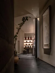 Elegant showroom with glass door, display cases, tables, and cabinets filled with vases, bottles, and other decorative items