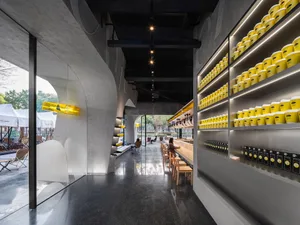 A dimly lit restaurant interior with a counter, chairs, and bottles on shelves, suggesting a modern design style