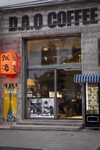 明亮內部空間採用磚牆設計，一位男子坐在窗前餐桌旁，周圍有其他人在休閒餐飲或社交環境中