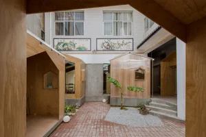 A classic building with a brick exterior, multiple rooms, a staircase, and windows, surrounded by potted plants, conveying a sense of history and charm