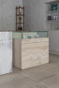 A clean and organized kitchen with a marble countertop, two cups, and three bottles arranged around it