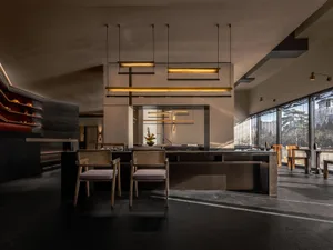 A bright and inviting kitchen dining space with a wooden table and chairs, a sink, refrigerator, and potted plants, offering ample seating for guests