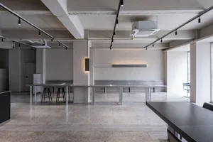 Empty modern room with a concrete floor, several chairs, and a minimalist atmosphere