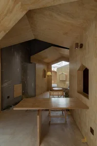 Cozy interior space with wooden walls and ceilings, featuring a dining area, living area, and lamps providing illumination