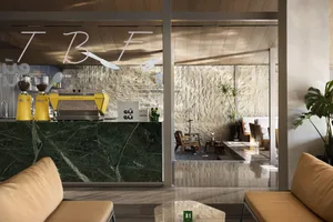 Modern coffee shop interior with a marble countertop, glass door, chairs, and a potted plant