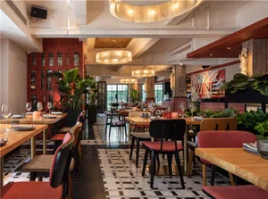 Modern restaurant interior with dining area, red accents, potted plants, and modern furniture