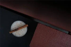 Cozy living space with a couch, table, and warm lighting, featuring a glass of milk and a cinnamon stick