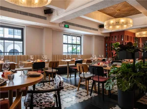 Elegant dining space with a large wooden dining table and chairs, surrounded by potted plants and wine glasses