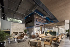 A spacious open area with seating options, wood, and metal elements, featuring potted plants and an inviting atmosphere