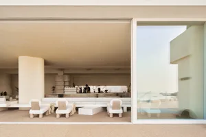 An open concept living area with a large window, chairs, a dining table, and a couch, flooded with natural light