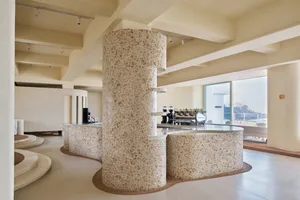 Open modern kitchen and dining area with stone walls, a large island countertop, and well-balanced lighting
