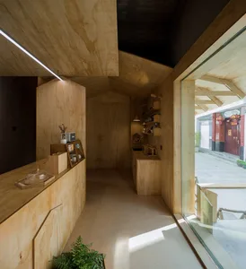 A warm and inviting interior design showroom with wooden walls and floors, featuring a dining table, chairs, and a potted plant