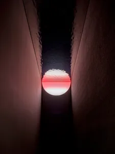 A darkened room with a small window showing a rising sun, creating a striking visual effect