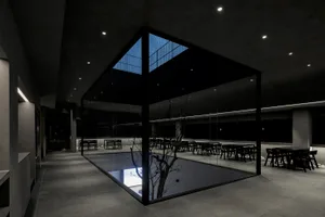 A modern restaurant with a large glass wall, chairs, and a dining table, flooded with natural light