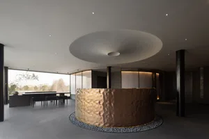 Modern hotel lobby with a circular gold metal structure, stone walls, and warm lighting