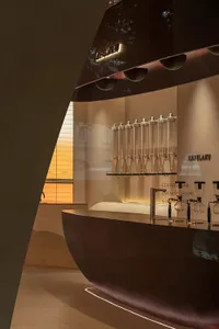 Inviting coffee shop interior with a large display case featuring various beverages and cups, surrounded by comfortable seating and decor