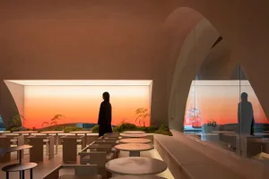 A warm and inviting dining area with multiple tables, chairs, and potted plants, lit by natural sunlight through windows