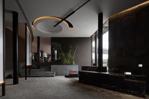 Warm and inviting living space with a fireplace, two chairs, and several potted plants