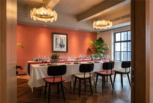 Sophisticated dining space with a long wooden table, multiple chairs, and wine glasses, surrounded by two potted plants