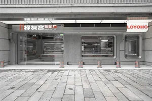 灰色工業建築，搭配大型家電展示窗，周圍環繞橘色柱子與現代氛圍