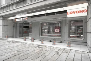 灰色外觀的現代工廠店面，擁有大型櫥窗展示與盆栽，牆上掛有電視