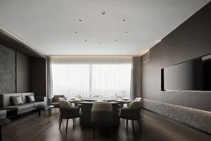 A modern dining area with a large wooden table, multiple chairs, and various table settings, surrounded by white walls and wooden floors