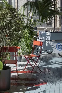 A comfortable outdoor seating area with multiple chairs and dining tables arranged in various positions, surrounded by natural scenery